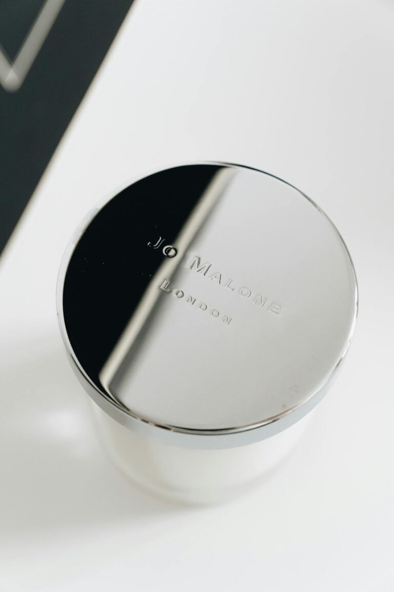 Premium Jo Malone candle with reflective metal lid in elegant lighting.